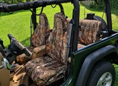 Realtree waterproof camo seat covers in a Jeep with front and rear seats covered, matching wheel cover on grass.