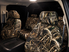 Full interior view of a vehicle at night, showing both front and rear seats completely protected by durable Realtree Camo seat covers.