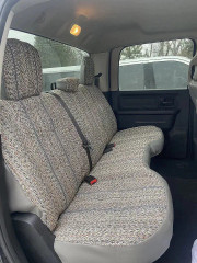 Rear bench seat of a pickup truck outfitted with a grey and tan woven saddle blanket seat cover, designed with precision cutouts for seatbelts.