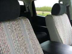 Close-up of front vehicle seats protected by durable, multi-colored tan and brown saddle blanket seat covers with a classic woven striped pattern.