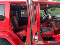 Interior view of a red Jeep featuring custom exotic seat covers with a striking red and black crocodile-embossed texture on the front and rear seats, matching the vehicle's bold exterior.