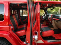 Interior view of a red Jeep featuring custom exotic seat covers with a striking red and black crocodile-embossed texture on the front and rear seats, matching the vehicle's bold exterior.
