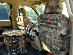 Luxury Line Kryptek camo seat covers on front seat backs with olive MOLLE webbing, flap pockets, and tan-brown scale pattern.