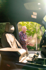 Car interior featuring Cordura seat covers, with a man standing outside the open door.