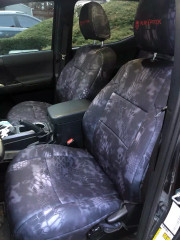 Front truck seats protected by Kryptek® "Typhon" camo seat covers, featuring a sleek dark-grey scale pattern and durable, custom-tailored construction.