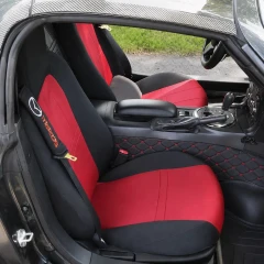 Sporty red and black neoprene seat covers installed in a convertible, featuring a custom logo on the headrest area and complementing the vehicle's performance interior.