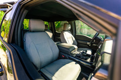 Front seats of a car fitted with durable Chevy Waterproof Cordura fabric seat covers in gray, viewed from the open door.