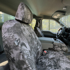 Kryptek Raid camo seat covers installed on truck front seats, featuring side airbag compatibility and a console cover.