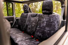 Rear bench seat of a vehicle protected with custom-fit Kryptek Typhon camo waterproof seat covers.