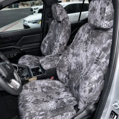 Front interior view of a vehicle showing custom-fit Kryptek® Camo seat covers on the front seats and center console for a unified, tactical look.