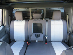 Neoprene seat covers on truck rear bench, charcoal sides with light gray grid panels, three headrests, and cupholder armrest.