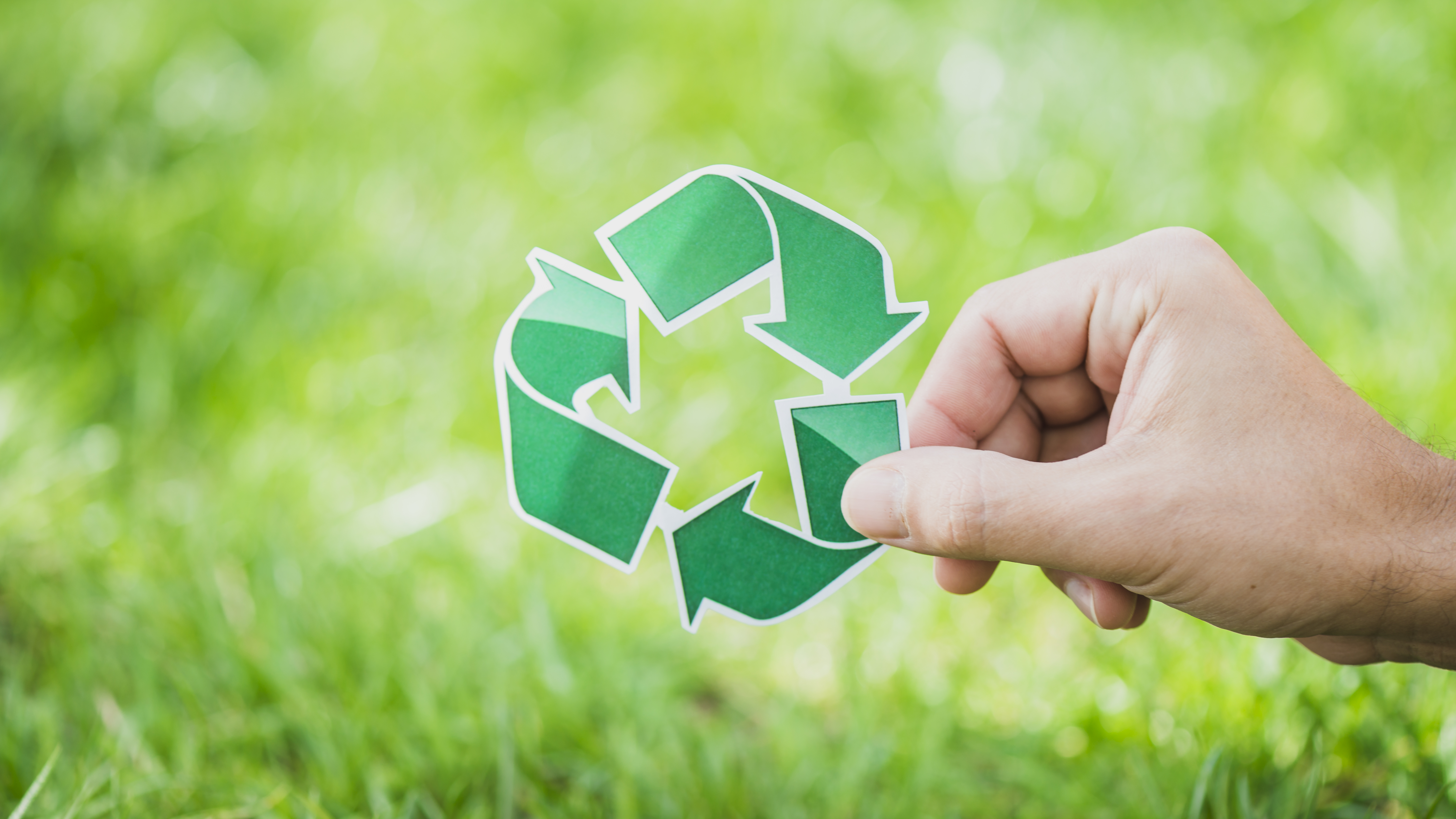 hand-holding-recycle-symbol-against-green-grass.jpg