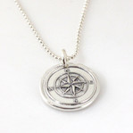 Compass Wax Seal Inspired Necklace laying on a white background