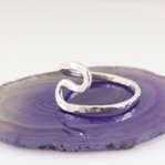 Sterling silver Rustic Wave Ring shown setting on a purple flat surface from another angle
