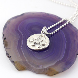 1/2" round silver paw print with a heart in the center on a silver bead style chain, laying on a purple agate slice, looking from right front side - ready to ship