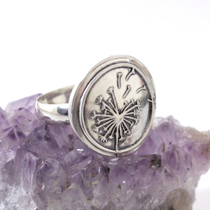 Dandelion Wax Seal Inspired Ring sitting on an amethyst crystal