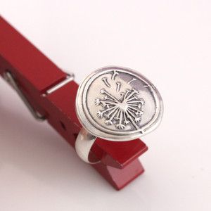 Dandelion Wax Seal Inspired Ring held up with a red clothes pin from a different angle