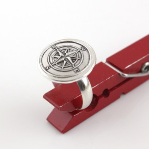 Compass Rose Wax Seal Inspired Ring held up in a red clothes pin