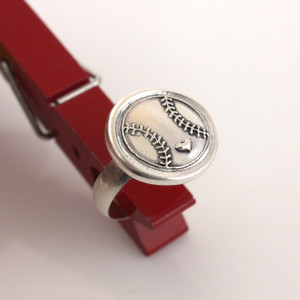 Baseball Love Wax Seal Inspired Ring held up in a red clothes pin on a white background from another angle