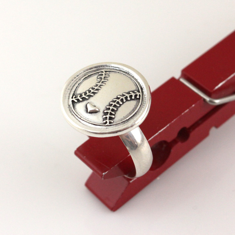 Baseball Love Wax Seal Inspired Ring held up in a red clothes pin on a white background