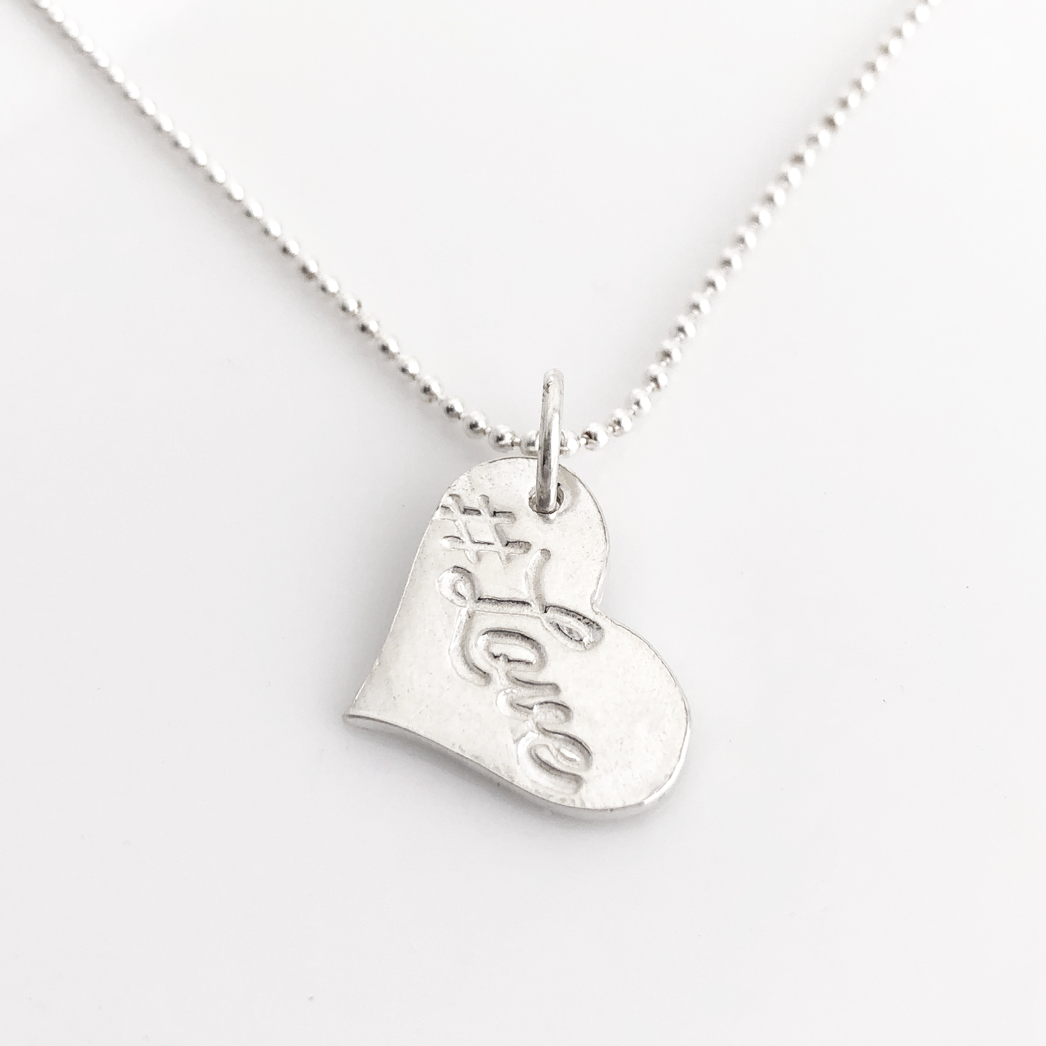 #Love Fine Silver Heart hanging from a sterling ball chain, shown on a white background.