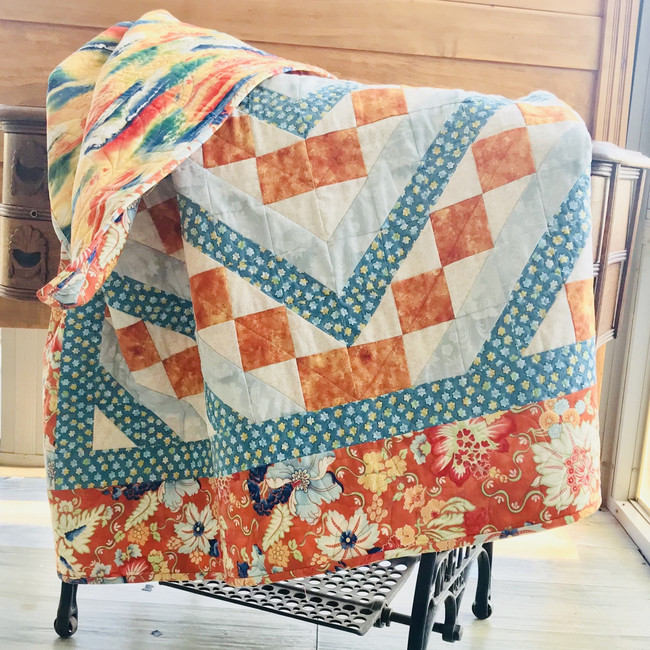 Orange squares form a diagonal pattern across the quilt. Highlighted with teal fabrics. Cotton fabric and cotton batting. Machine sewn