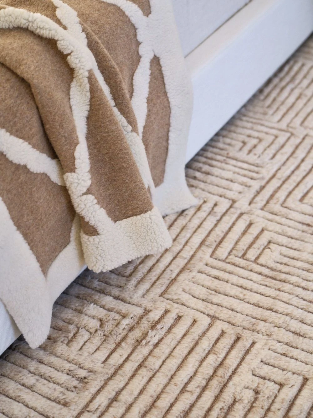 Wool throw draped over a bed onto a rug