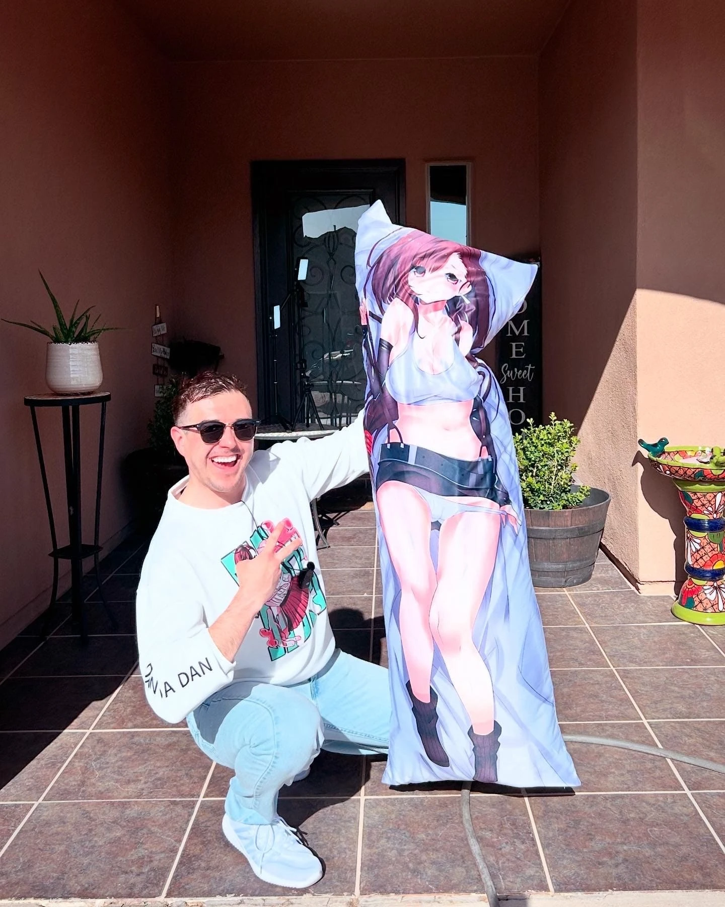 Person smiling while holding an anime body pillow