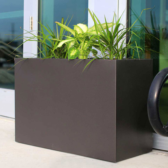Brisbane extra large fiberglass planter box in brown finish with greenery on modern patio