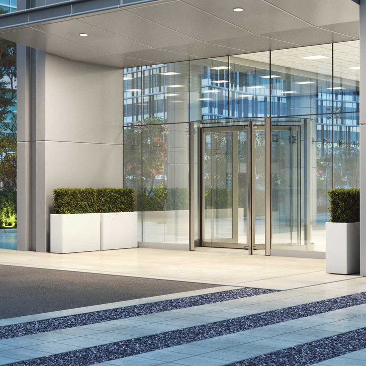 Amesbury tall narrow fiberglass planter box in white finish placed at modern building entrance
