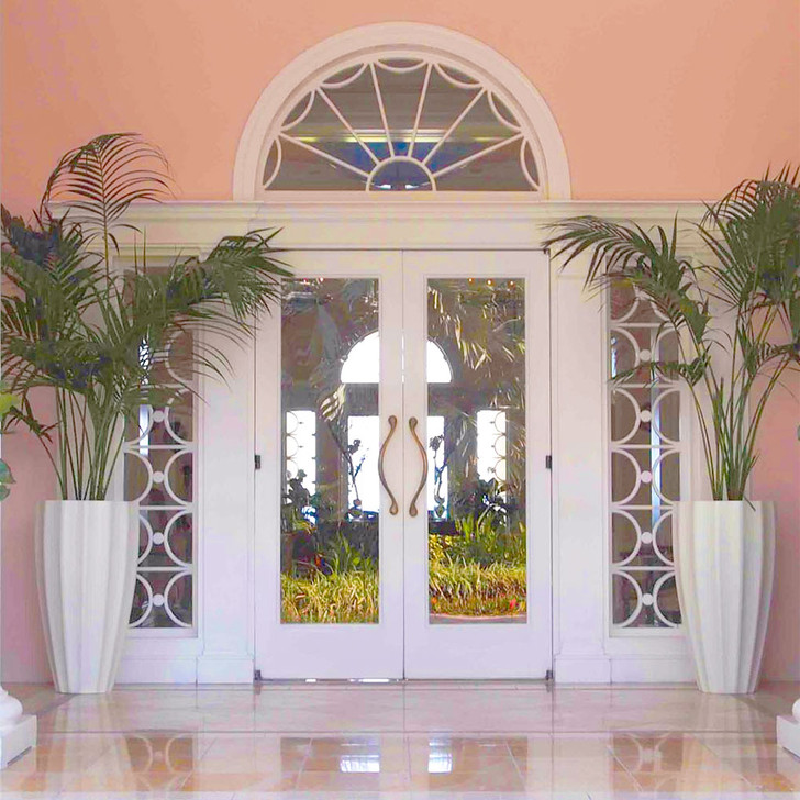 Pair of San Jose tall fluted fiberglass planters in white finish placed indoors by double doors with palms