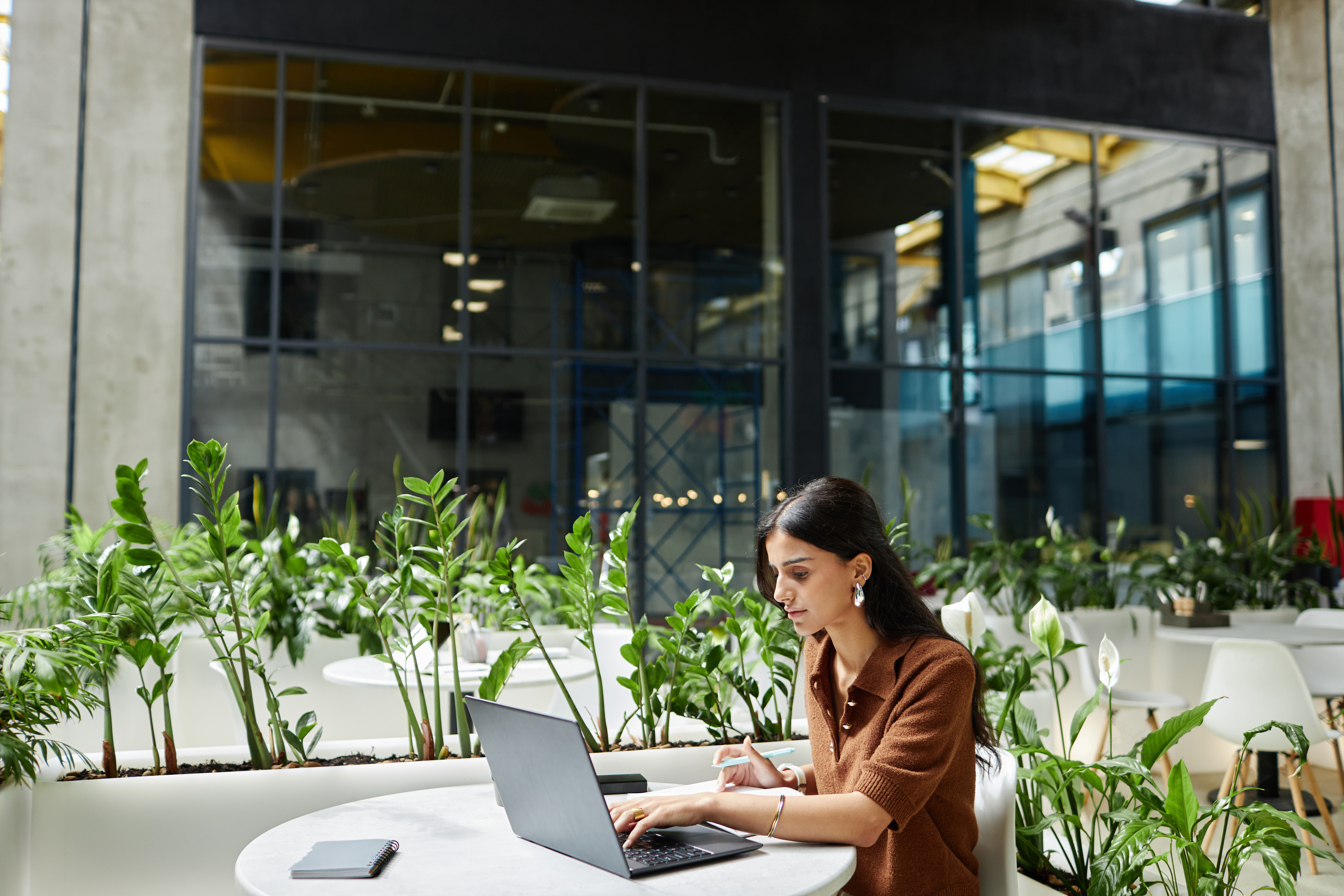 woman working at a functional co-working space surrounded by plants