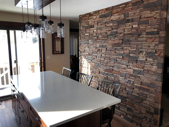 Dining room wall paneled with our Lexington Dry Stack Stone Wall panels in the sienna color.