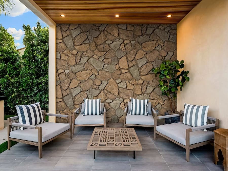 Small patio with chairs featuring Sardis Fieldstone Faux Stone Wall Panel in Bonanza.