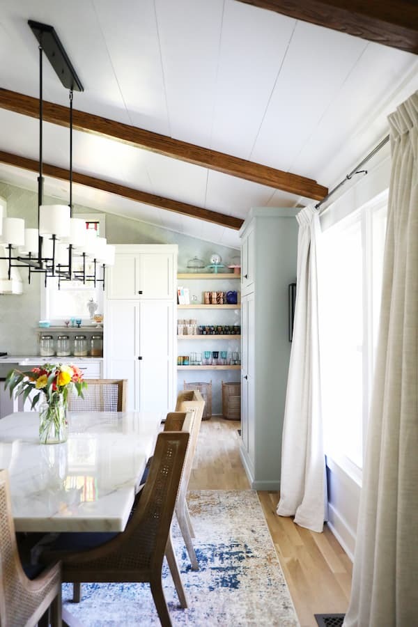 Modern dining room featuring Old Barn Faux Wood Beams, finished by customer, installed on a white vaulted tongue-and-groove ceiling.