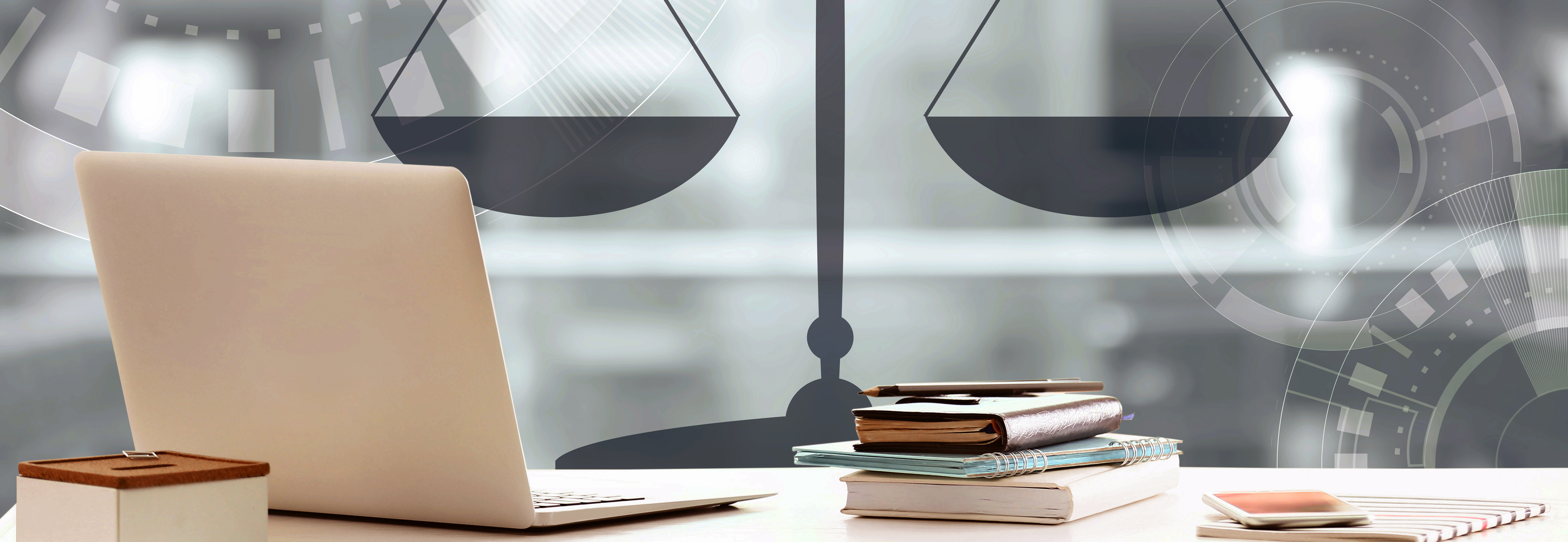 laptop, books, phone on desk with imagery of the scales of justice and gears in the background