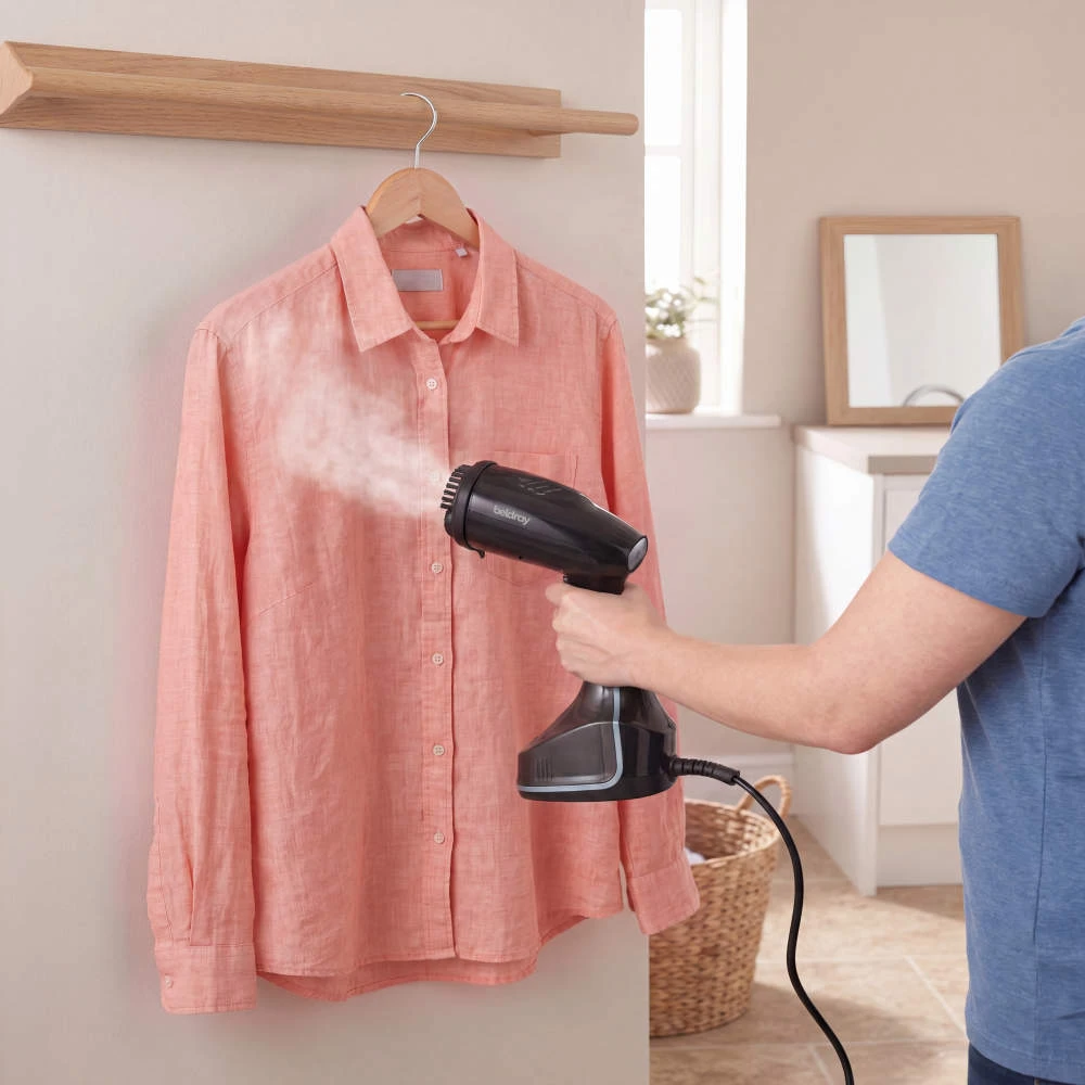 Garment steamer used on a pink button-up shirt