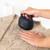 Handheld electric fabric shaver being used on knitted jumper