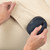 Hand using blue fabric shaver to remove bobbles from beige jumper sleeve