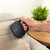 Hand using compact fabric cleaner on beige sofa cushion