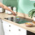 Hand cleaning induction hob with blue brush in modern UK kitchen