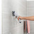 Electric cleaning brush in use on tiled bathroom wall
