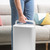 White portable dehumidifier being carried by handle in living room