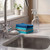 Stack of blue and grey cleaning cloths beside sink with spray bottle