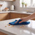 Hand wiping crumbs from kitchen worktop with blue microfibre cloth