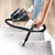 Cylinder vacuum cleaning carpeted stairs with hose; shown in home use