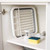White plastic dish rack with brush and sponge, stored on kitchen cupboard shelf.