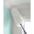 White fluffy duster cleaning ceiling corner, shown against pastel wall, home cleaning product