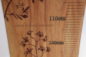 Laser engraved detail on a blackwood height chart with wording 'loved beyond measure' and Australian native plants kangaroo paw and banksia laser engraved.