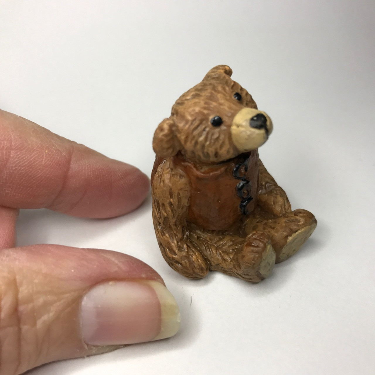 Itty bitty brown bear wearing a light brown "leather" vest